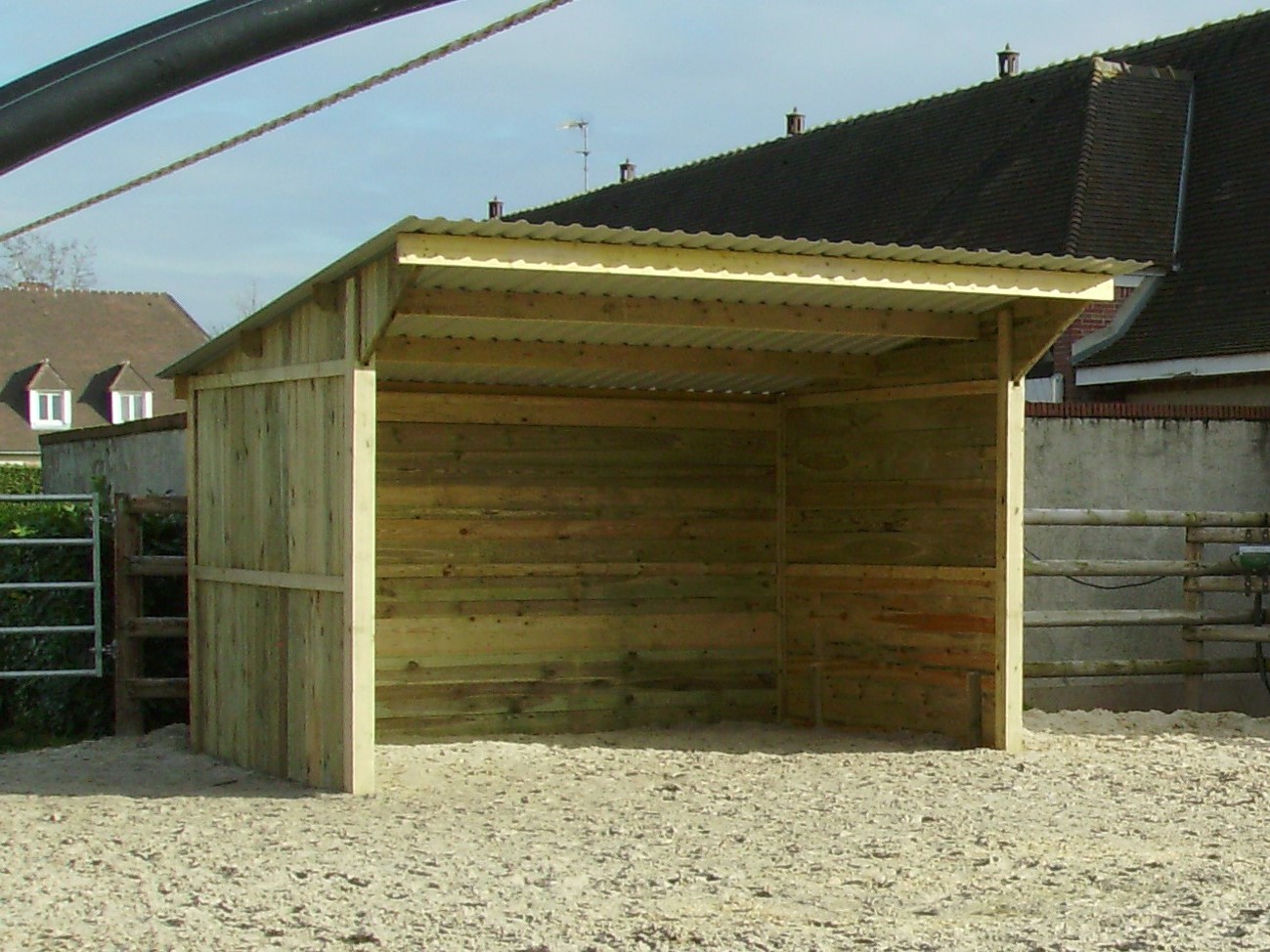 Abri pour chevaux à clins en bois, vu de près et très légèrement de profil.