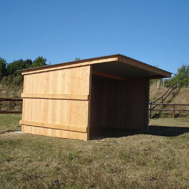 Abri à bardage à côté d'une clôture en bois, vue de très près de son profil droit.