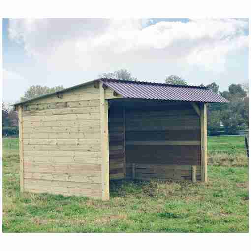 Abri pour chevaux en bois avec clins, toit double pente, au milieu d’un terrain verdoyant.