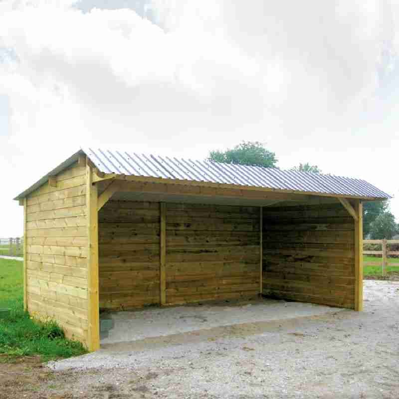 Abri pour chevaux en bois avec clins, toit double pente, vu de près et légèrement de profil.