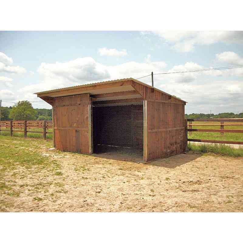 Abri pour chevaux avec retour en façade, vu de profil, avec une clôture en bois derrière.