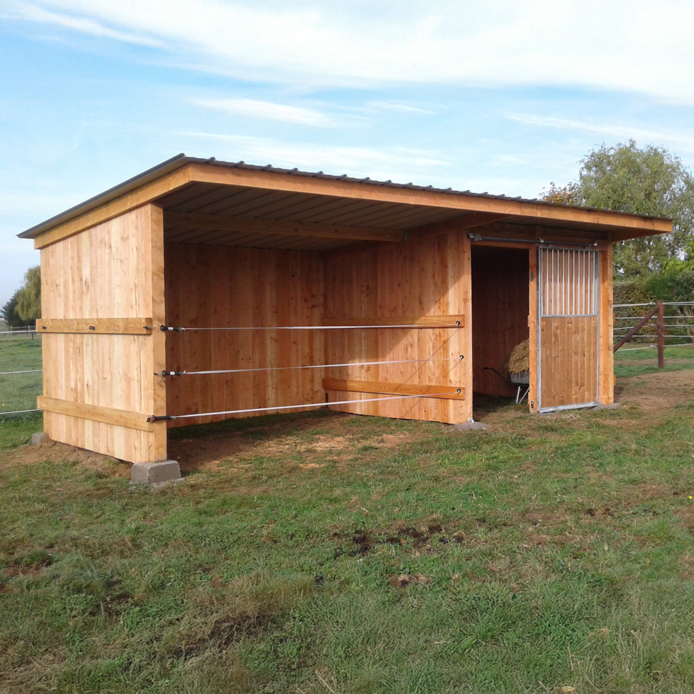 Abri box pour chevaux, vu de face et légèrement de profil, à côté d’une clôture HSW1.