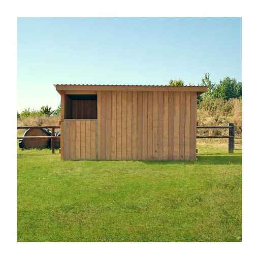 Box à bardage, vu de face, à côté d’une clôture en bois et de bottes de foin.