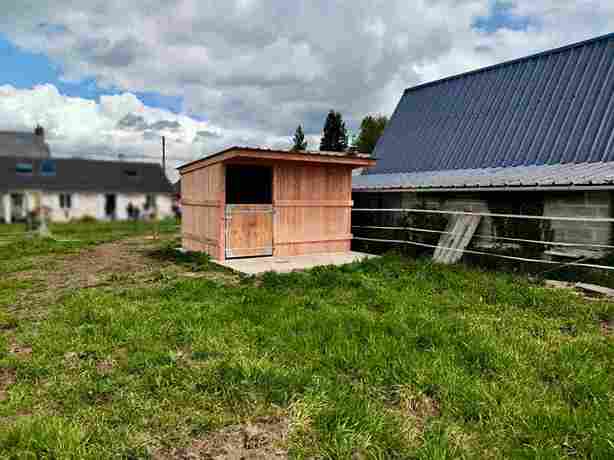 Box à bardage, vu de profil, au milieu du terrain d’une résidence citadine.