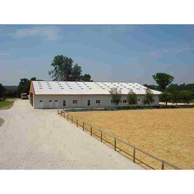 Carrière accompagnée d’une clôture à 1 lisse en bois, avec un hangar blanc en arrière-plan.