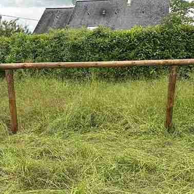 Clôture à 1 lisse en bois, vue en pleine largeur, avec des l’horizons en arrière-plan.