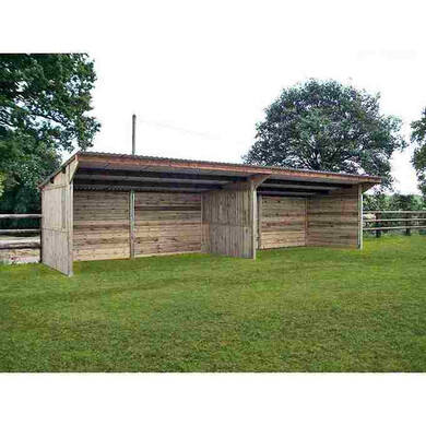 Grand abri pour chevaux avec séparation, vue de près, avec une clôture en bois derrière.