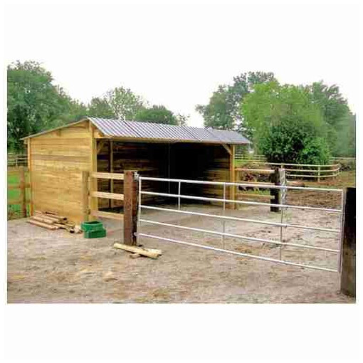 Abri pour chevaux en bois avec clins, toit double pente, collé à une clôture et une barrière.
