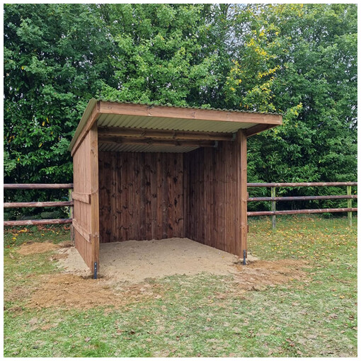 Abri chevaux en madrier, vue de près et de face, avec une clôture à 3 lisses en arrière-plan.