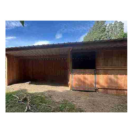 Abri box pour chevaux, vu de très près et de face, avec un arbre en arrière-plan.