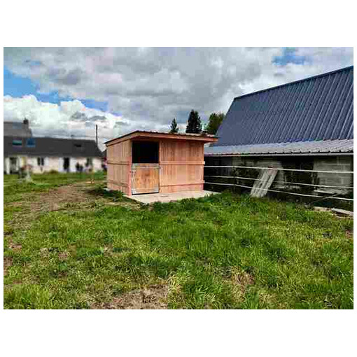 Box à bardage, vu de profil, au milieu du terrain d’une résidence citadine.