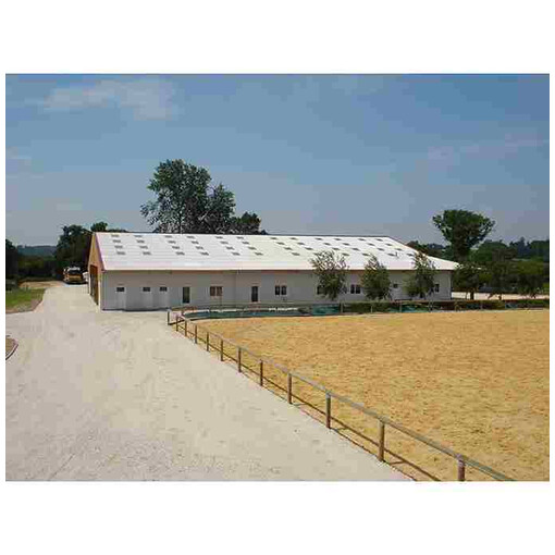 Carrière accompagnée d’une clôture à 1 lisse en bois, avec un hangar blanc en arrière-plan.