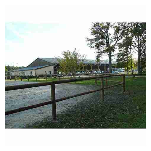Clôture de carrière à 2 lisses en bois, installée à proximité d’une carrière et de chevaux.