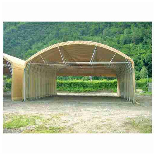 Tunnel de stockage en PVC, vu de face à mi-distance, avec une forêt en arrière-plan.