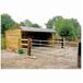 Abri pour chevaux en bois avec clins, toit double pente, collé à une clôture et une barrière.